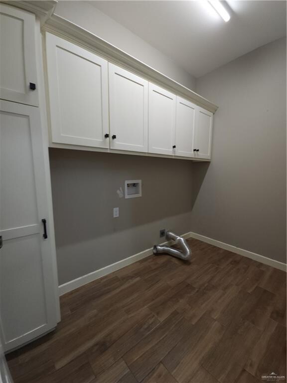 clothes washing area featuring dark wood-type flooring, cabinets, and washer hookup