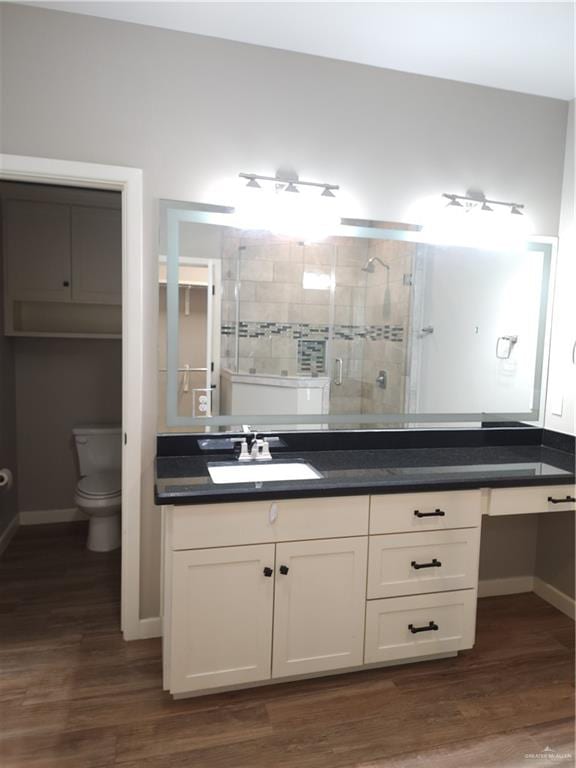 bathroom with vanity, hardwood / wood-style flooring, a shower with door, and toilet