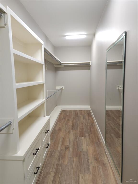 walk in closet with dark hardwood / wood-style floors