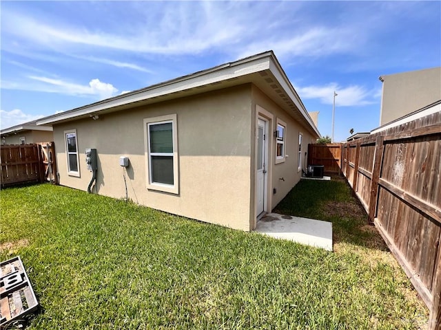 back of property featuring stucco siding, a fenced backyard, and a lawn