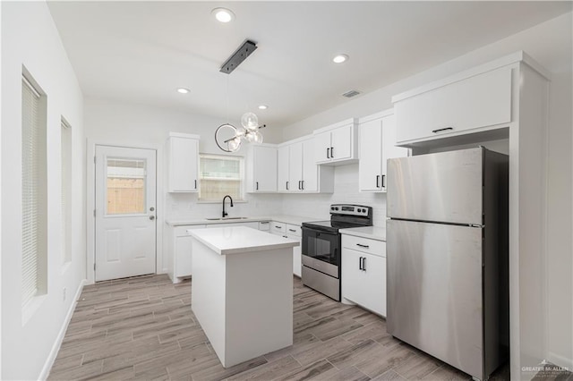 kitchen featuring white cabinets, stainless steel appliances, a sink, visible vents, and a notable chandelier