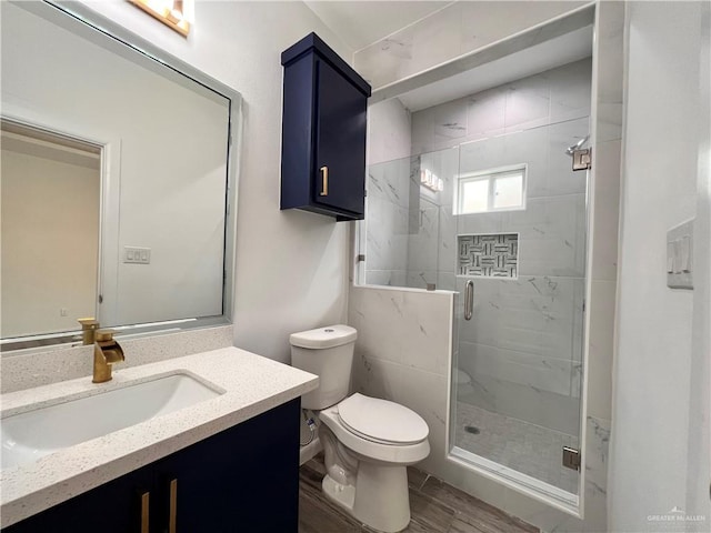bathroom with wood finished floors, vanity, toilet, and a stall shower