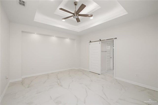 unfurnished bedroom with marble finish floor, a raised ceiling, a barn door, and visible vents
