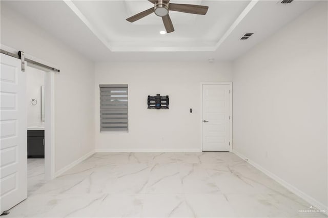 unfurnished room with marble finish floor, ceiling fan, a tray ceiling, and visible vents