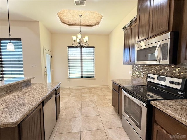 1813 Harvard Ave, Mcallen, TX 78504 - kitchen with stainless steel appliances, dark brown cabinetry, tasteful backsplash, a chandelier, and decorative light fixtures