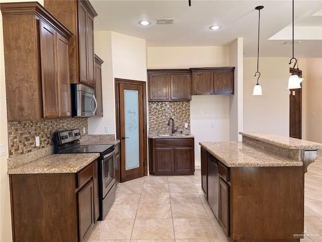 1813 Harvard Ave, Mcallen, TX 78504 - kitchen with appliances with stainless steel finishes, a sink, backsplash, a kitchen island, and light stone countertops