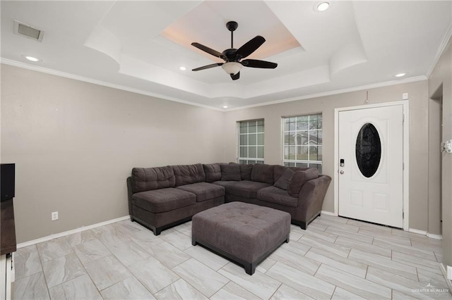 living area with ceiling fan, visible vents, a raised ceiling, and baseboards