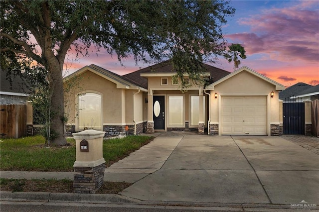 view of front of home featuring a garage, stone siding, driveway, and stucco siding