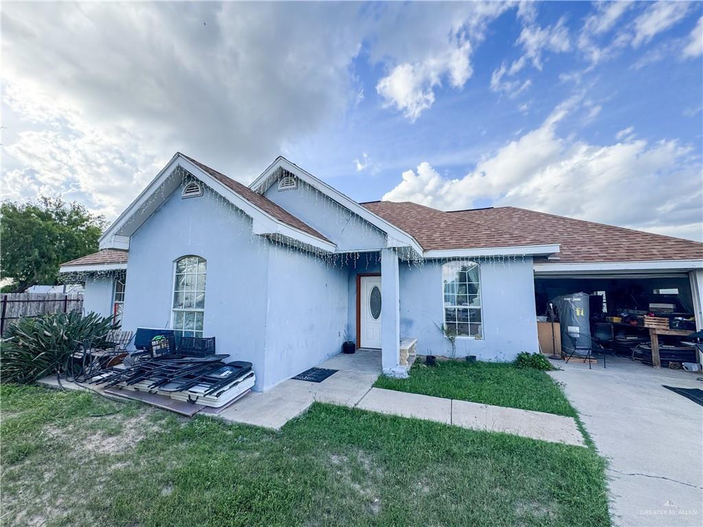 325 N Alamo St, Alton, TX 78573 - ranch-style house featuring concrete driveway, a garage, a shingled roof, and stucco siding