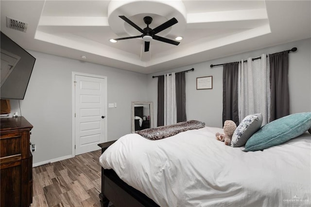 bedroom featuring a raised ceiling, hardwood / wood-style flooring, and ceiling fan