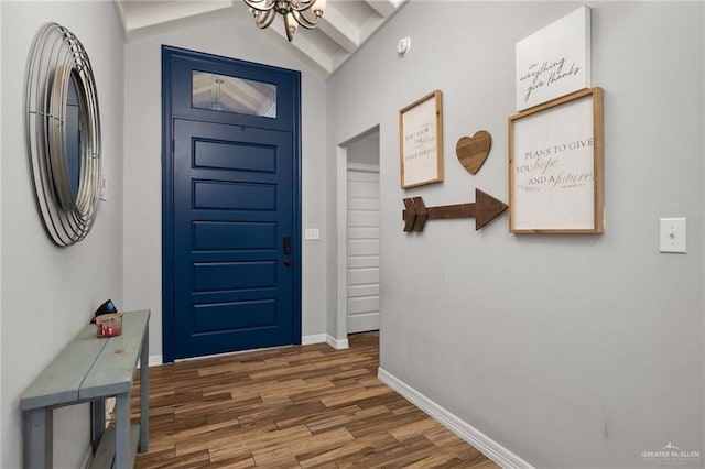 entryway featuring a notable chandelier, dark wood-type flooring, and vaulted ceiling