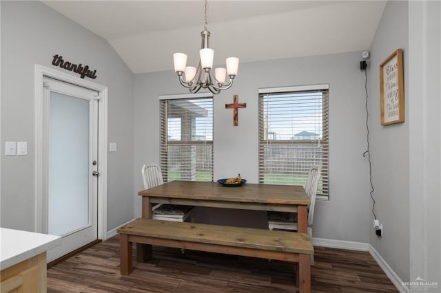 dining space with dark hardwood / wood-style flooring, lofted ceiling, and an inviting chandelier