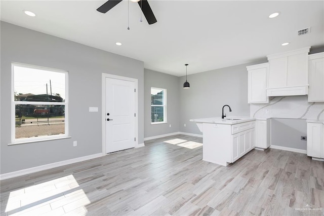 814 N Martinez Ave, Weslaco, TX 78596 - kitchen with ceiling fan, a peninsula, white cabinets, light wood finished floors, and a sink