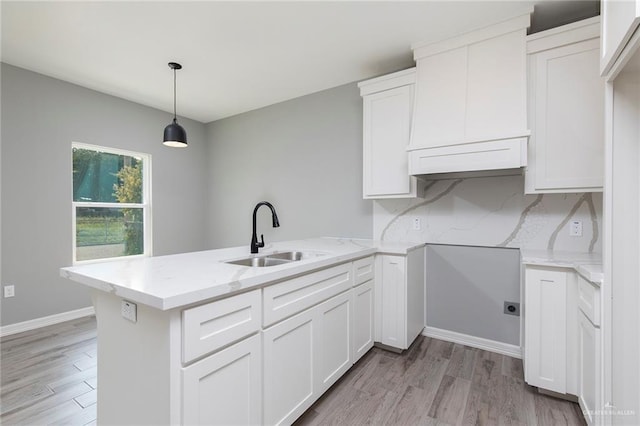814 N Martinez Ave, Weslaco, TX 78596 - kitchen with a sink, a peninsula, light wood-style flooring, and white cabinetry