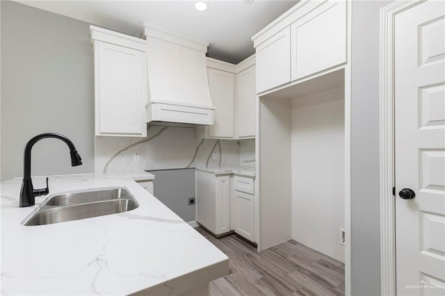 814 N Martinez Ave, Weslaco, TX 78596 - kitchen with a sink, custom range hood, light stone counters, light wood-type flooring, and white cabinetry
