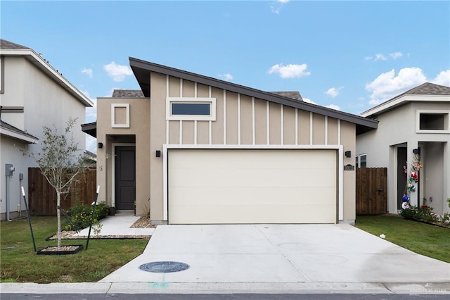 view of front facade with board and batten siding, a front yard, fence, and an attached garage