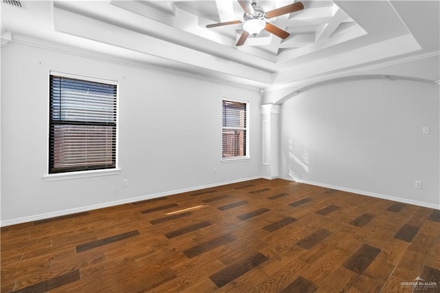 empty room with ceiling fan, a raised ceiling, dark wood-type flooring, and crown molding