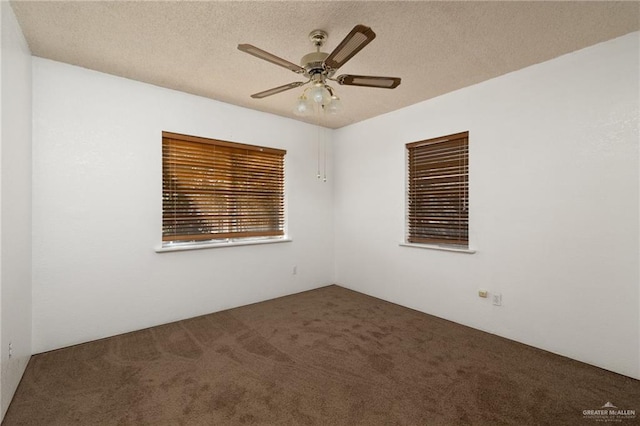 spare room with ceiling fan, a textured ceiling, and dark colored carpet