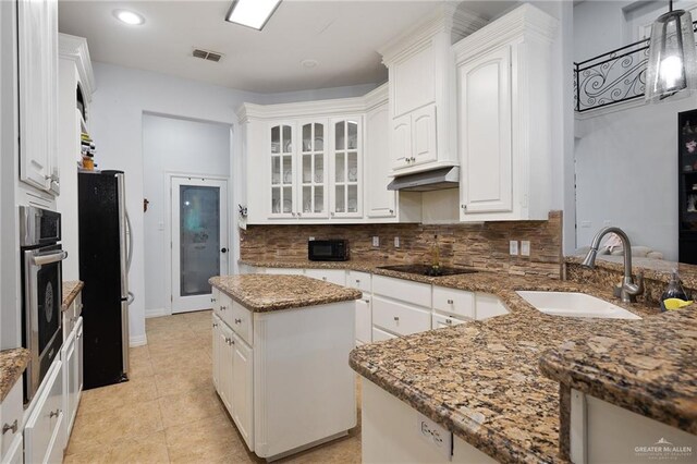 kitchen featuring white cabinetry, sink, stainless steel appliances, dark stone countertops, and a kitchen island