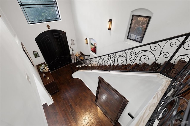 foyer entrance with a towering ceiling and dark hardwood / wood-style floors