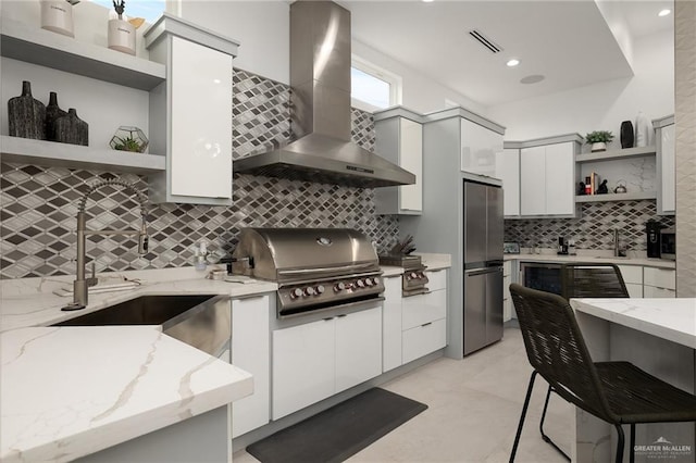 kitchen with white cabinetry, light stone counters, and wall chimney exhaust hood