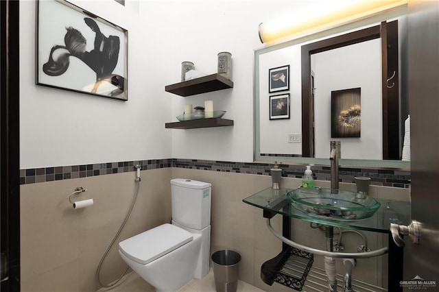 bathroom featuring sink, tile walls, and toilet