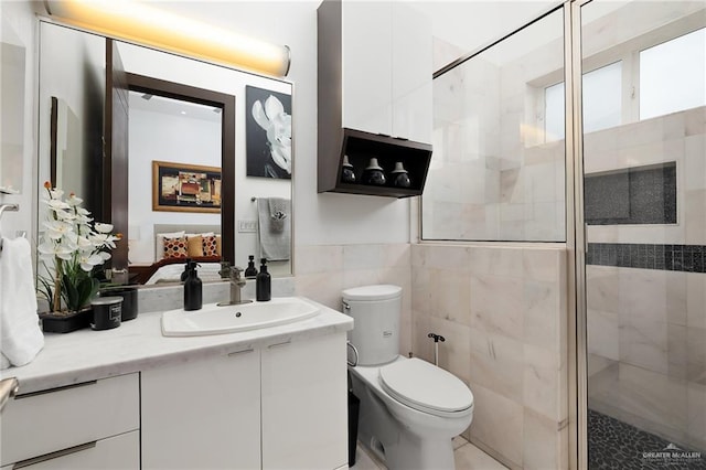 bathroom with vanity, toilet, a shower with door, and tile walls