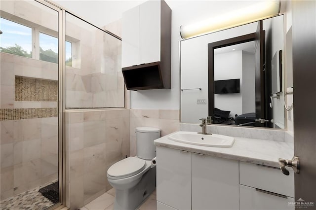 bathroom with vanity, a shower with door, toilet, and tile walls