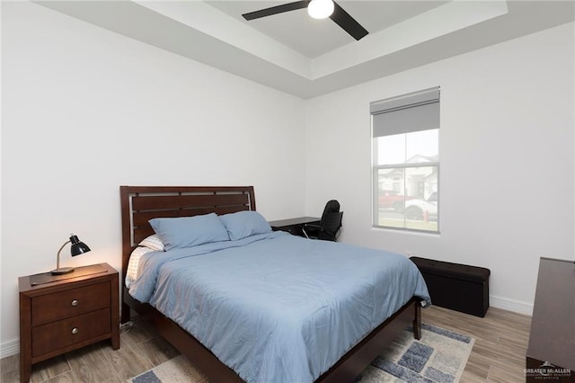 1806 E 28th St, Mission, TX 78574 - bedroom featuring a tray ceiling, light wood-type flooring, baseboards, and a ceiling fan