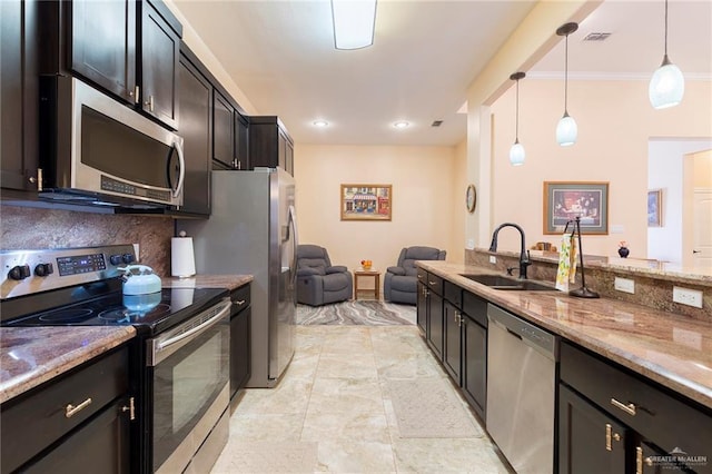 kitchen with decorative light fixtures, stainless steel appliances, tasteful backsplash, a sink, and light stone countertops