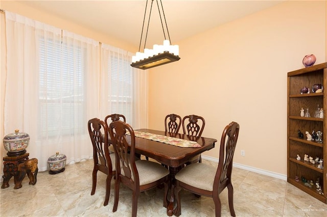 dining space featuring baseboards and a notable chandelier