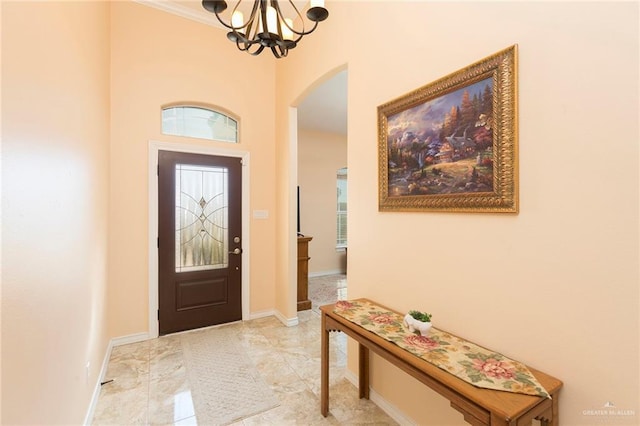 foyer with a chandelier, arched walkways, and baseboards