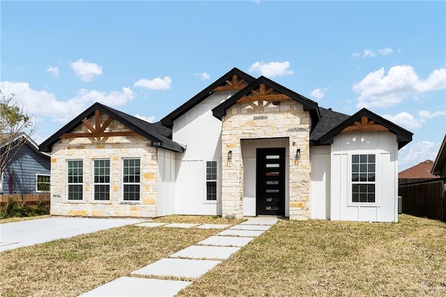 view of front of home with a front yard, fence, board and batten siding, and stone siding