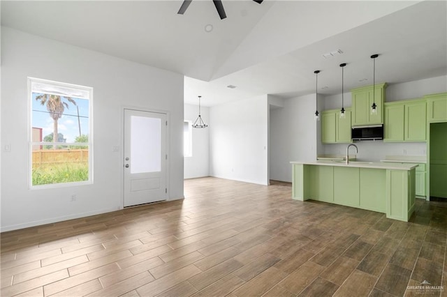 803 Ava Dr, La Feria, TX 78559 - kitchen with green cabinetry, stainless steel microwave, ceiling fan, wood finished floors, and an island with sink