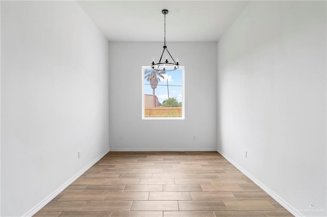 803 Ava Dr, La Feria, TX 78559 - empty room with a chandelier, light wood-style flooring, and baseboards