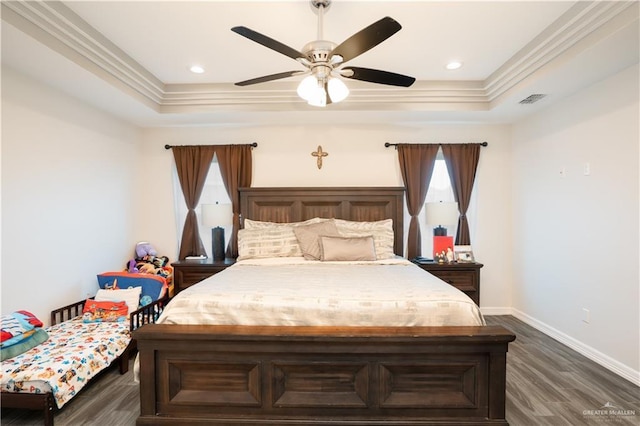 bedroom with ornamental molding, dark wood-type flooring, and a tray ceiling