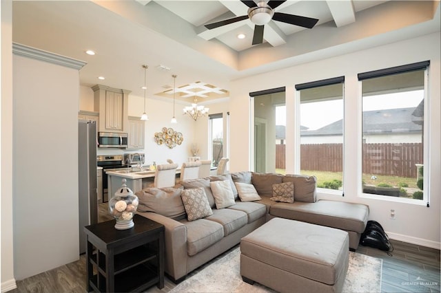 living room with ceiling fan with notable chandelier, a wealth of natural light, and light hardwood / wood-style flooring