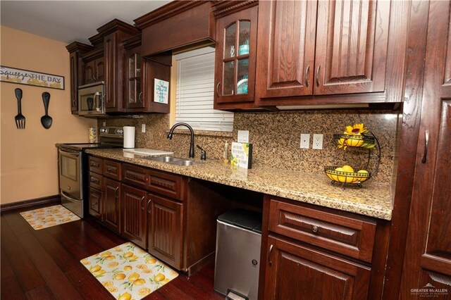 kitchen with appliances with stainless steel finishes, dark hardwood / wood-style flooring, backsplash, light stone counters, and sink