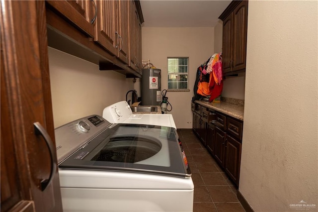 washroom with water heater, dark tile patterned floors, cabinets, and independent washer and dryer