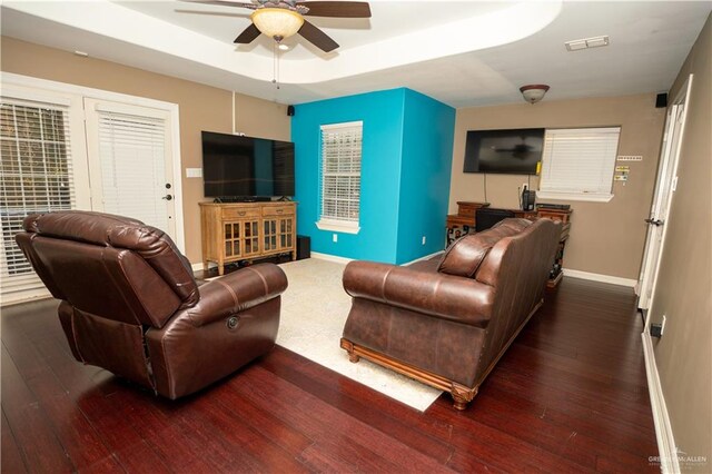 living room featuring a tray ceiling, ceiling fan, and dark hardwood / wood-style floors