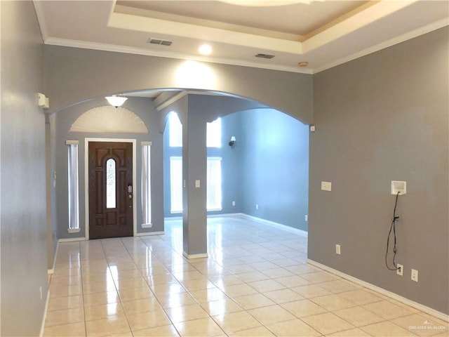 foyer entrance with light tile patterned floors, a raised ceiling, and crown molding