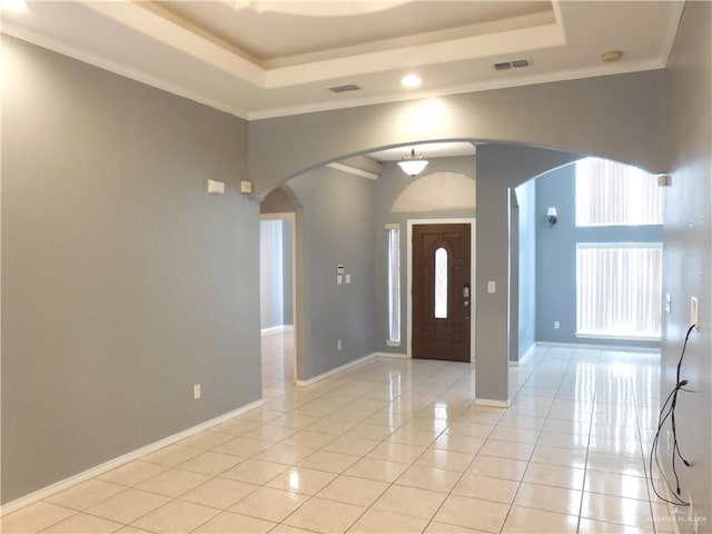 entrance foyer with a raised ceiling, light tile patterned flooring, and ornamental molding