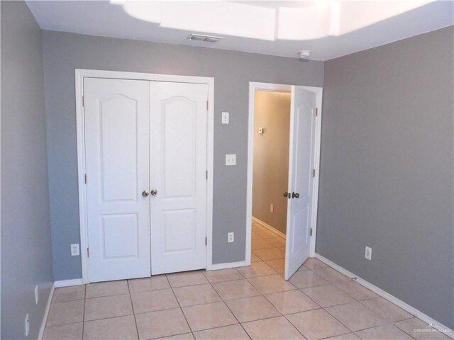 unfurnished bedroom with light tile patterned floors and a closet