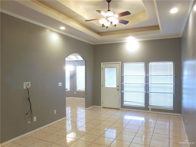 interior space featuring a tray ceiling, ceiling fan, crown molding, and light tile patterned flooring