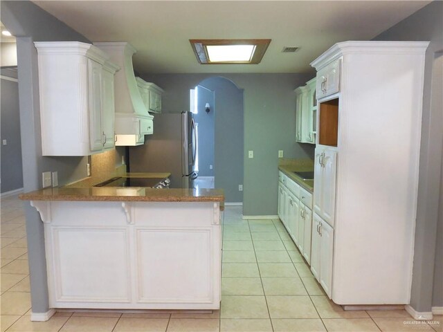 kitchen with kitchen peninsula, white cabinetry, light tile patterned flooring, and extractor fan