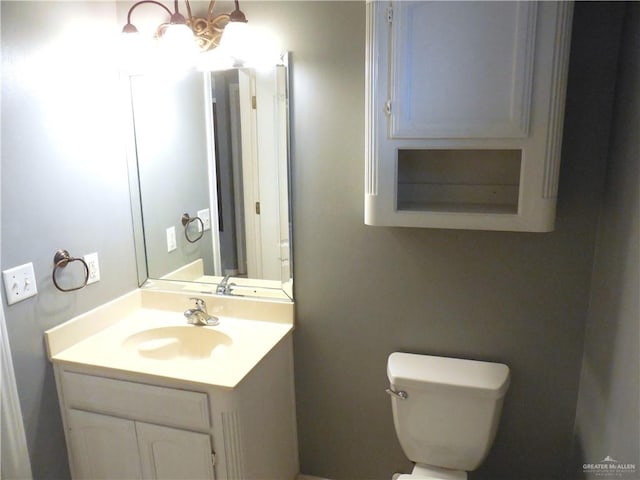 bathroom featuring an inviting chandelier, vanity, and toilet