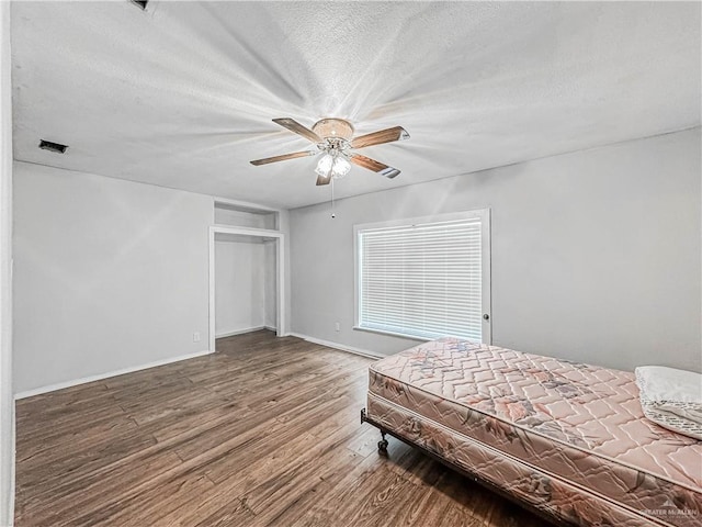 unfurnished bedroom featuring wood-type flooring, a textured ceiling, and ceiling fan