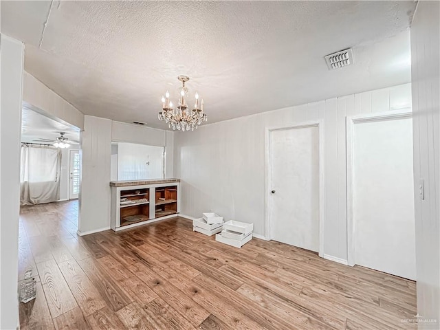 interior space with a textured ceiling, ceiling fan with notable chandelier, and light wood-type flooring