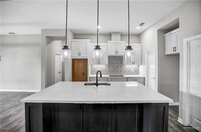 kitchen with an island with sink, hanging light fixtures, and sink