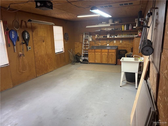 garage with a workshop area, a garage door opener, and wood walls